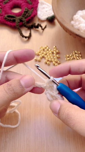 Chaining white yarn to start the next popcorn stitch.