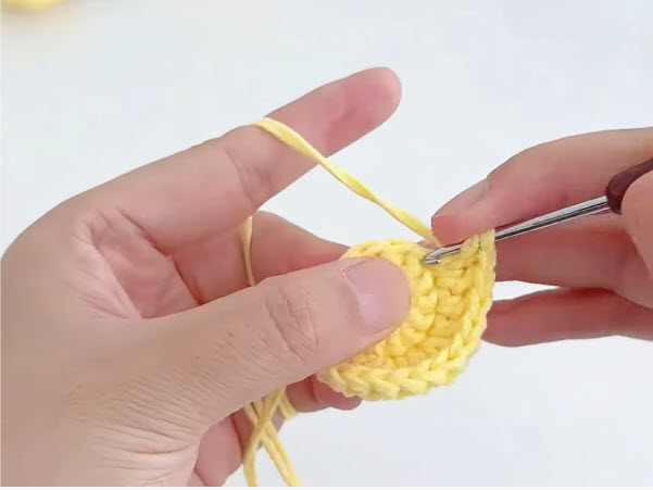 Closing the top of the yellow crochet chick with a drawstring.