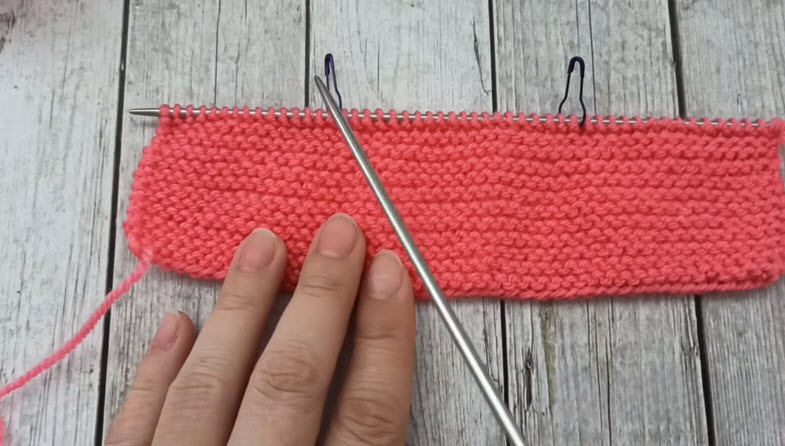 Coral knitted panel with stitch markers on needle
