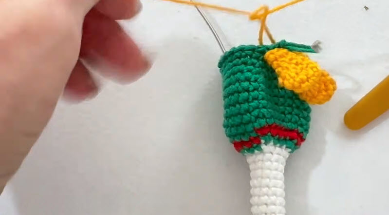 Crocheting green amigurumi duck body with wing