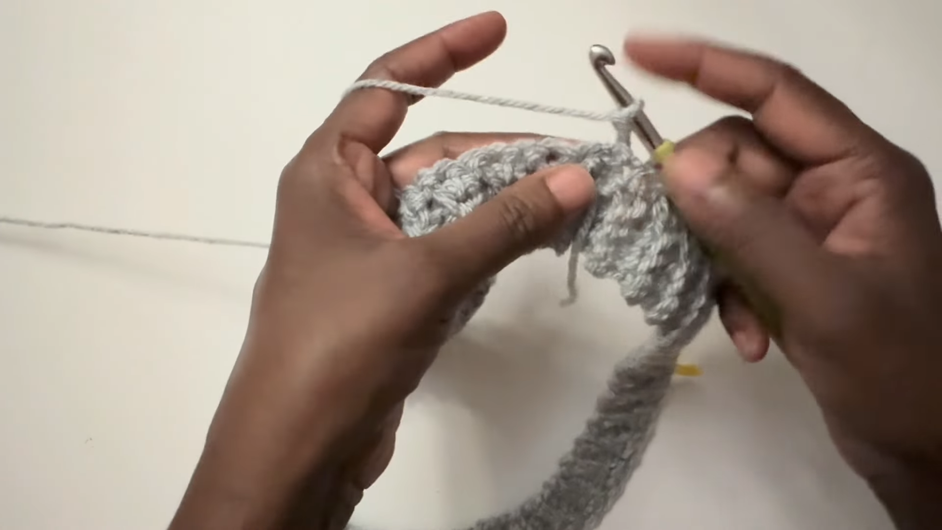 Crocheting round on gray sweater sleeve piece