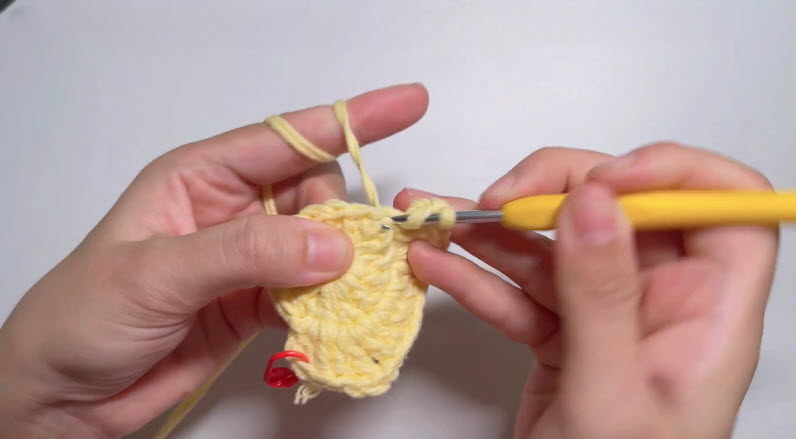 Crocheting star point on yellow crochet basket