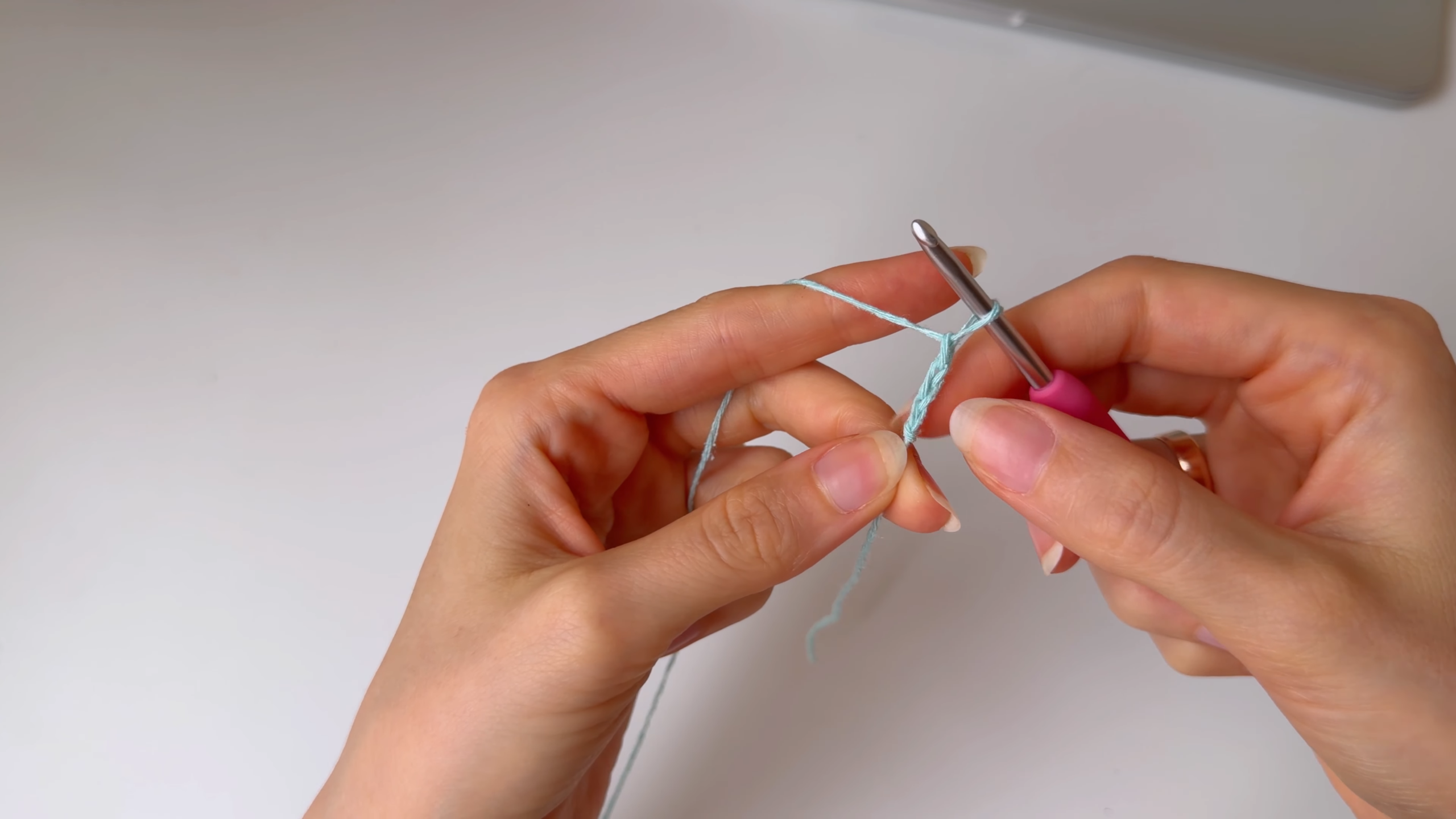 Crocheting with mint yarn and pink hook