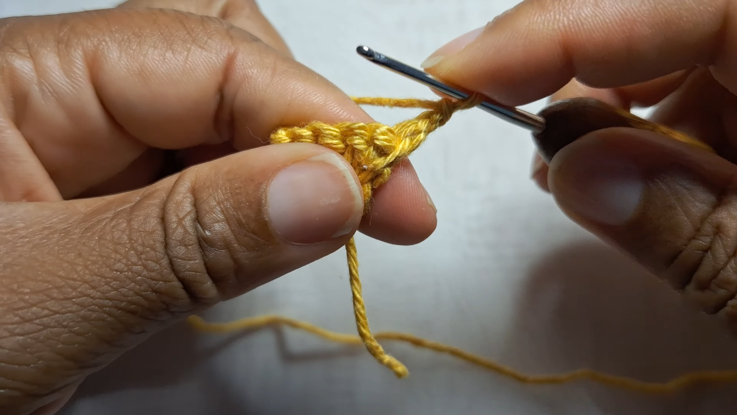 Crocheting yellow yarn with metal hook