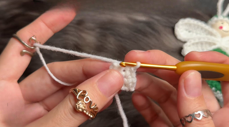 Fingers working single crochet stitches with gold hook.