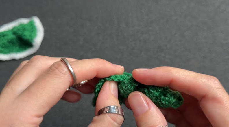 Finished green and white crochet slice piece held in hand.