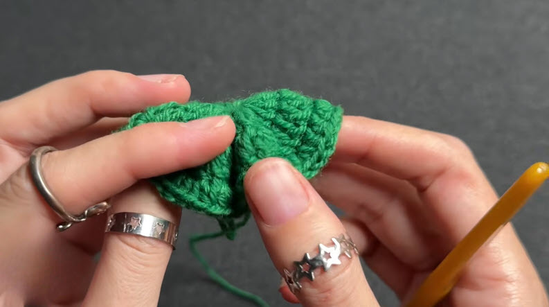 Green crochet circle with double crochet stitches, gold hook resting on top.