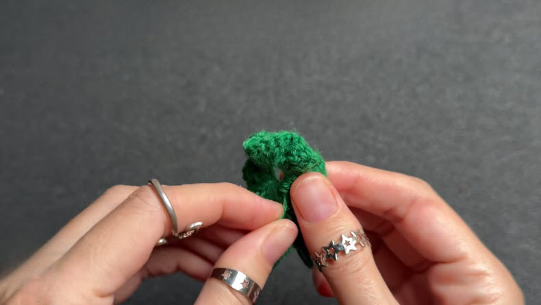 Hands crocheting 3 chain stitches with green yarn and gold hook.