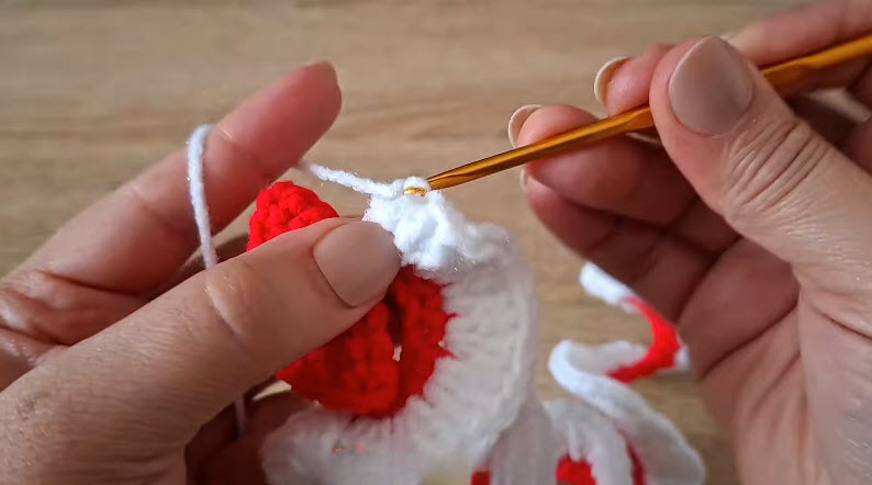 Hook joining white and red crochet pieces at seam.