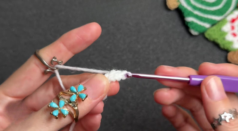 Hook working 11 double crochet stitches into a white ring.