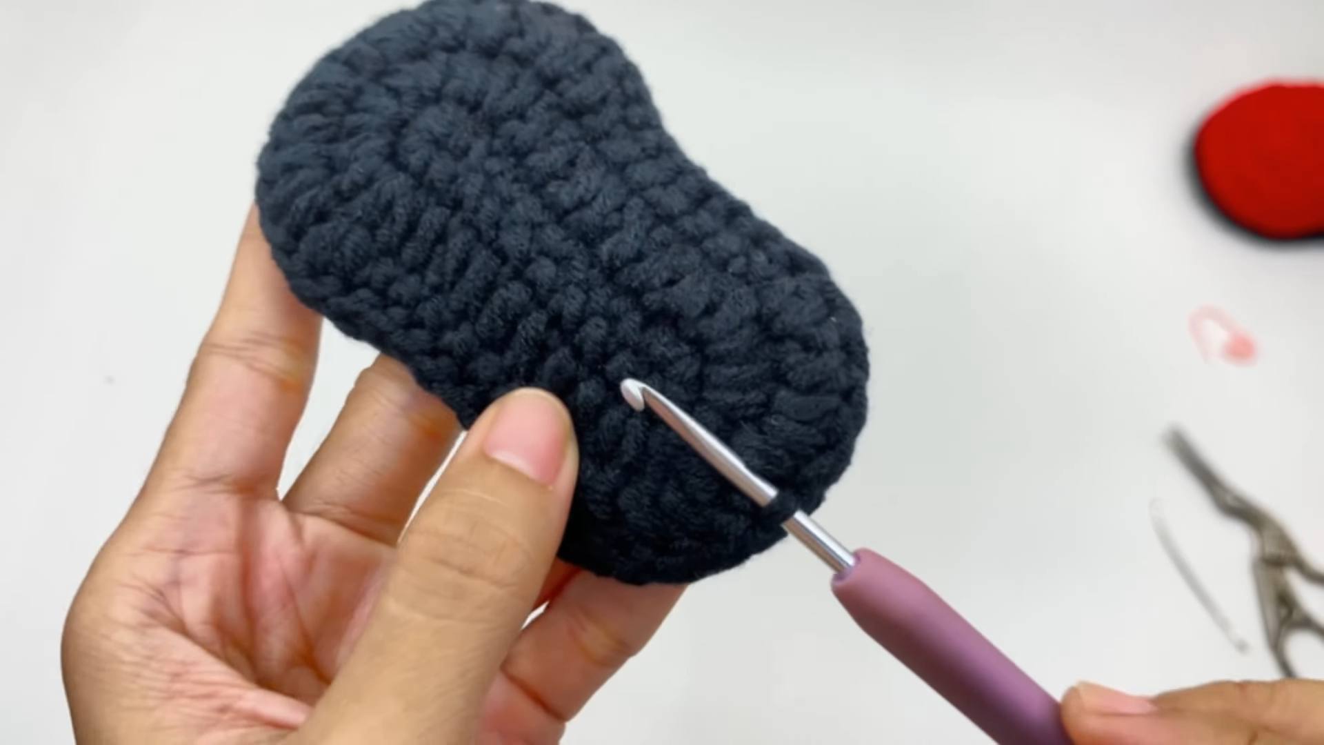 Sewing red sole onto crochet baby bootie