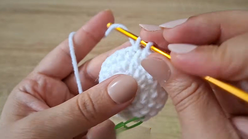 Single crochet stitches on white amigurumi ball, green marker visible.