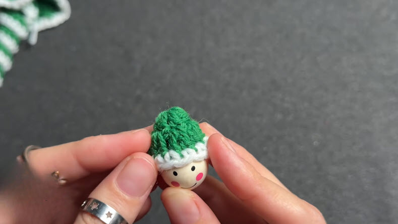 Small green crochet hat shape with double crochet stitches.