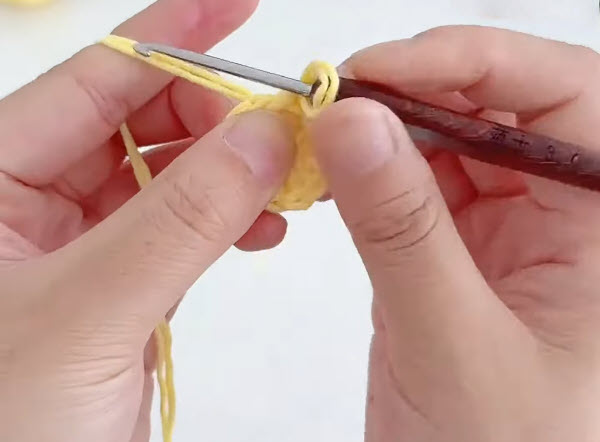 Starting a slip knot with yellow yarn on a crochet hook.