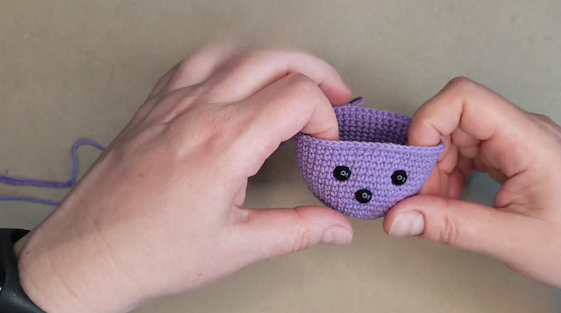 Three black safety eyes set into the purple head.