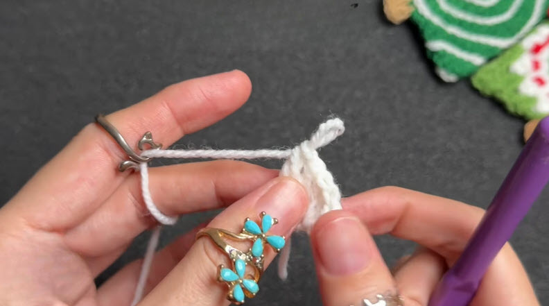White crochet ring with starting chain, hook resting nearby.