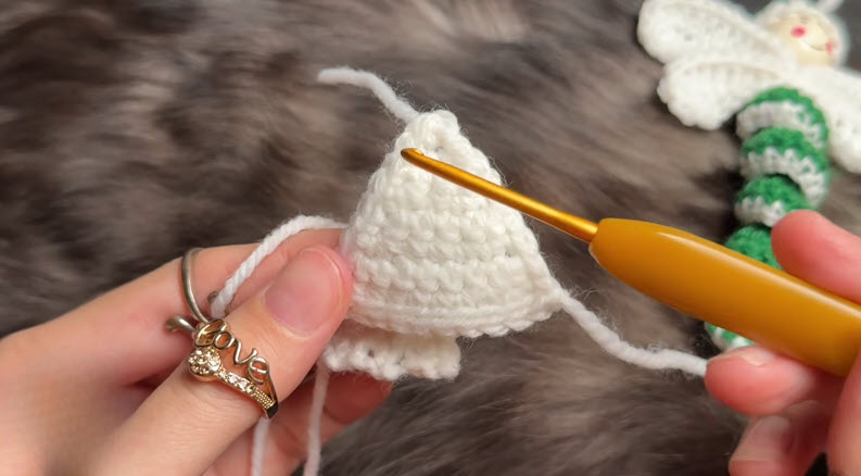 White crocheted cone shape held with hook at the top point.