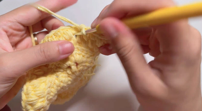 Working rounds on yellow crochet star basket