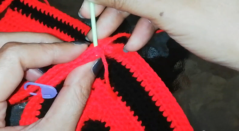 Closing the red and black piece with a lavender stitch marker nearby.