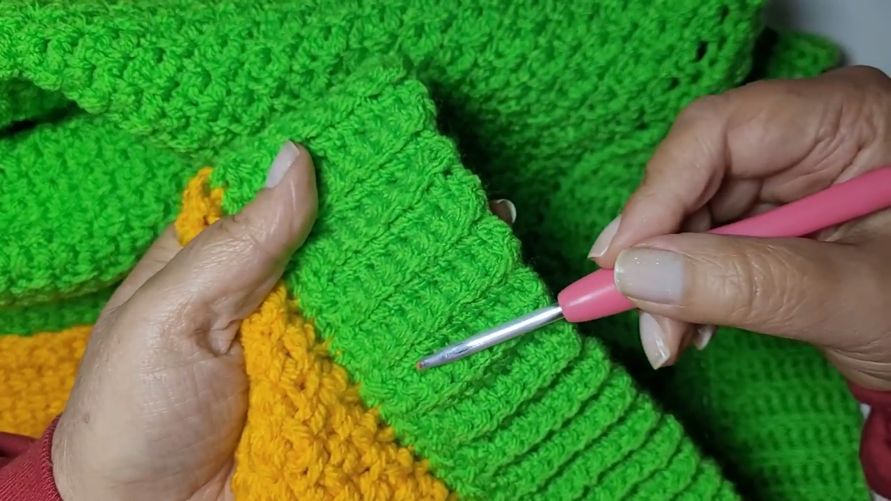 Crocheting the ribbed green cuff edge with a pink hook