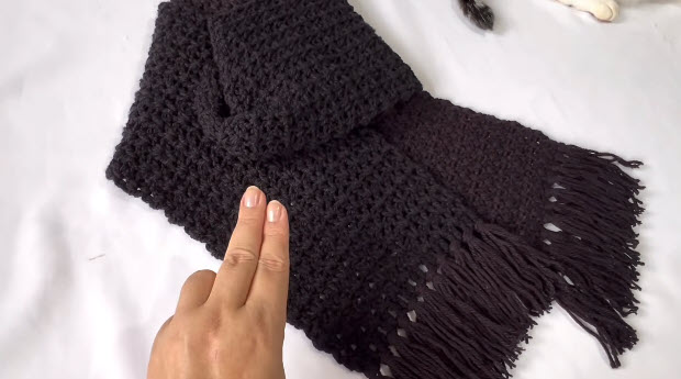 Finished black scarf laid flat with fringe on the ends.