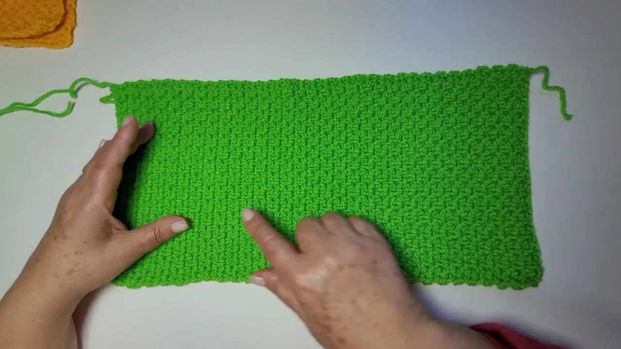 Finished green cardigan body panel laid flat on a table