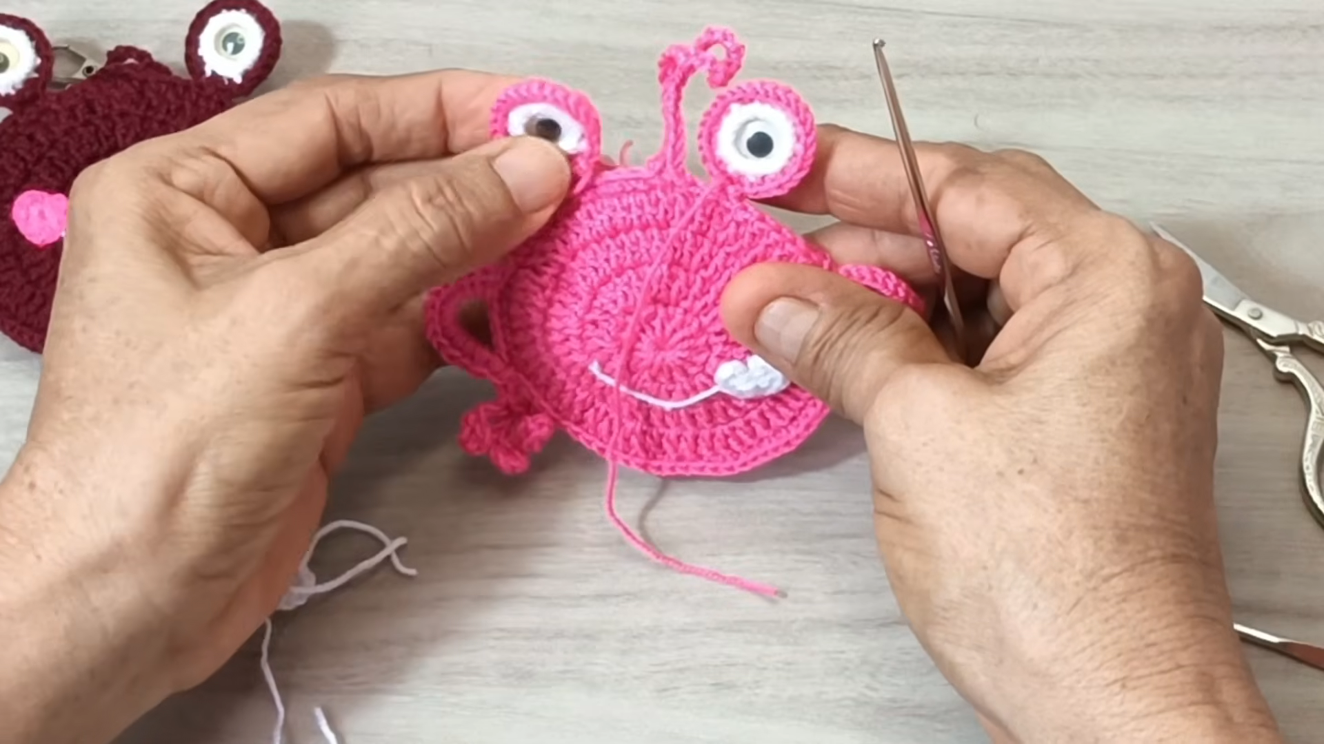 Finished pink frog with a white smile and cheek.