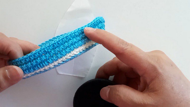 Folding the blue piece with a white stripe along the edge.