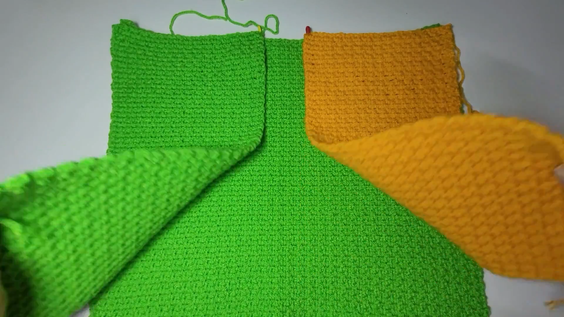 Green and yellow crochet panels laid out ready to join into a cardigan