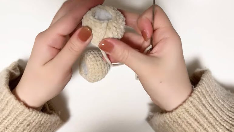 Crochet dog keychain pattern step 3 sewing the head to the body with a needle