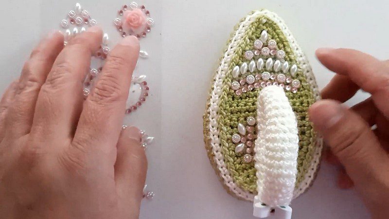 Pearls and gems placed on the crochet iron pattern with the white handle attached.