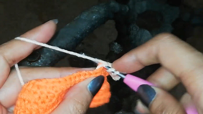 Pulling the cream yarn through with the pink hook.