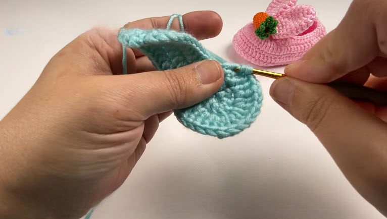 Oval sole of the crochet bunny baby shoes worked around the blue base with a gold hook.