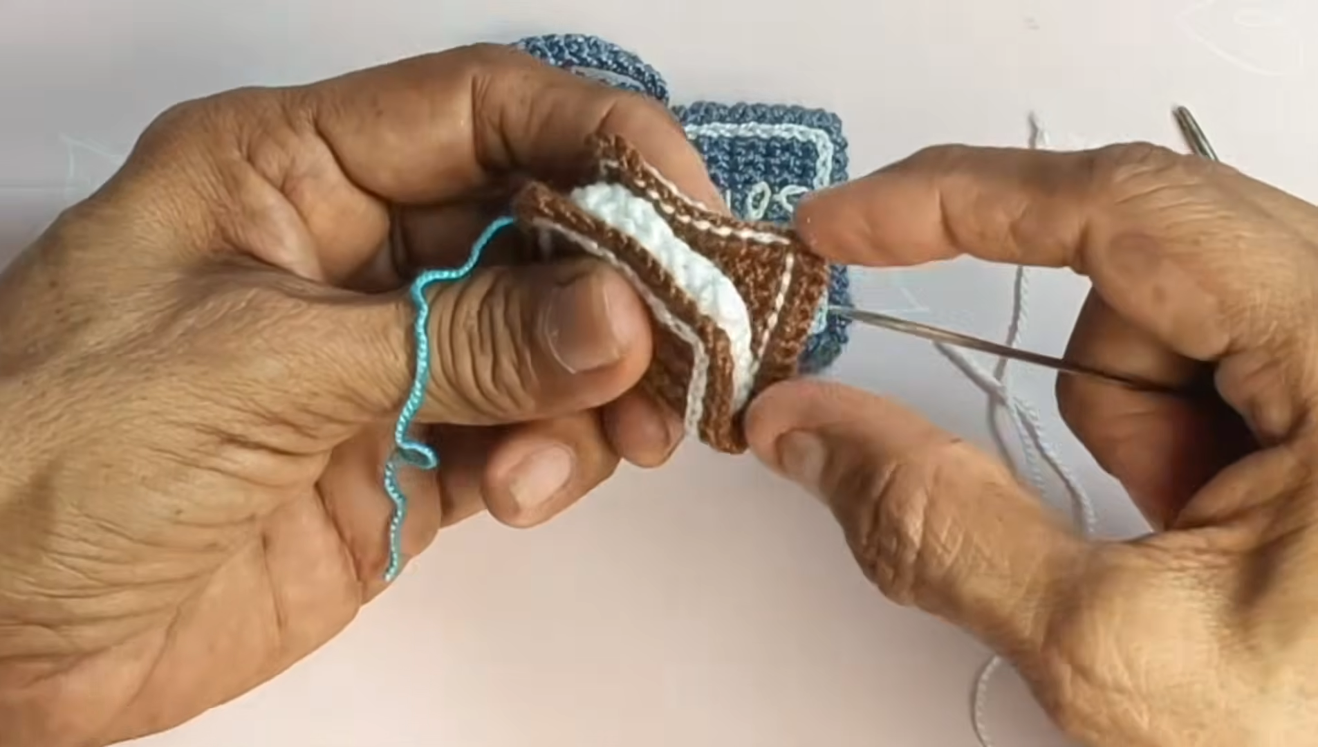 Sewing the layers onto the blue piece with a needle.