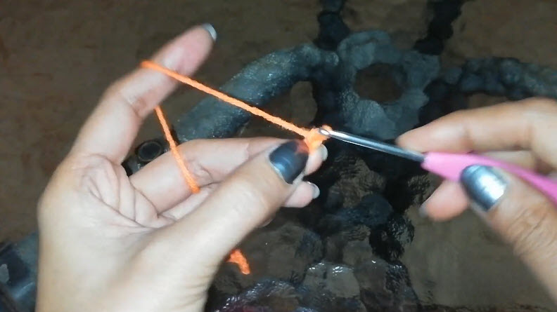 Starting the chain with orange yarn wrapped over the finger.