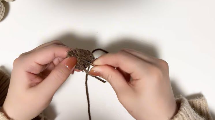 Brown yarn threaded through the needle to sew the small ear piece