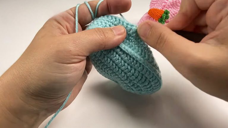Tight blue stitches rising into the walls of the baby bootie.