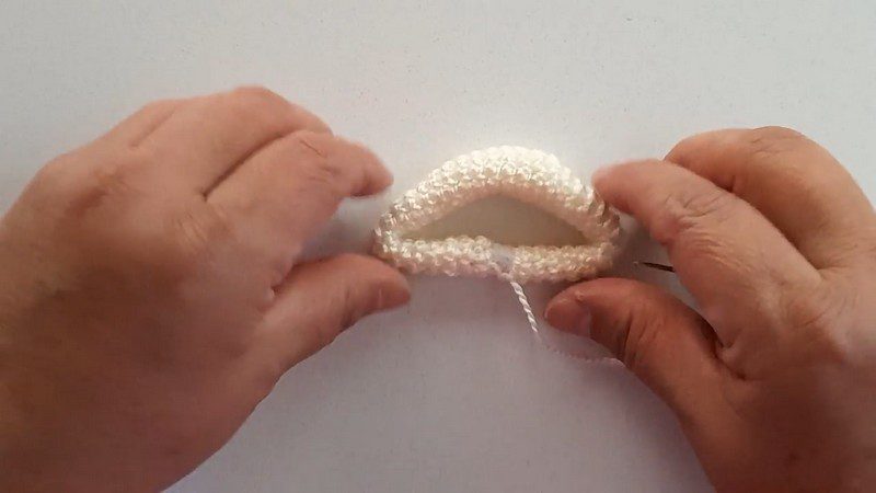 White crocheted piece stitched closed around the plastic insert.
