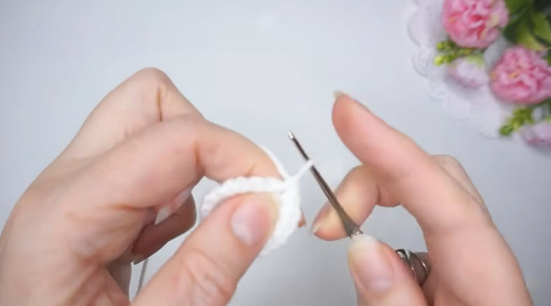 Working the first white rounds of the crochet budgie into a small flat circle.